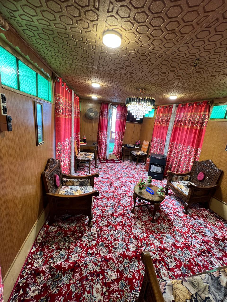 Houseboat sitting room with carved wooden chairs, chandelier and red Kashmiri carpet