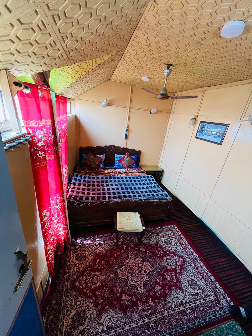 Quiet bedroom with carved wooden bed and red Kashmiri carpet